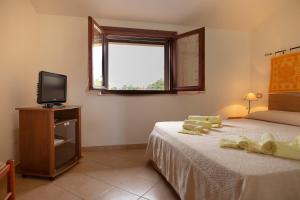 1 dormitorio con 1 cama, TV y ventana en Agriturismo i doni del mandorlo en Alguer