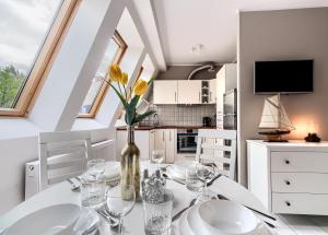 a dining room with a table with glasses and a vase with yellow flowers at Apartament Kajuta - NoclegiSopot in Sopot