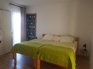 una camera da letto con un letto con una coperta verde sopra di Hamo Apartments & Soba a Lumbarda (Lombarda)