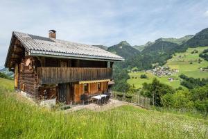 an old wooden house on a hill with mountains in the background at Knusperhäuschen Höfen-hüsle in Raggal