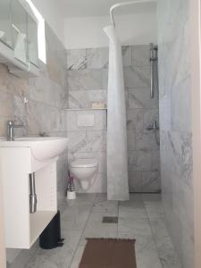 ルンバルダにあるHamo Apartments & Sobaの白いバスルーム(トイレ、シンク付)