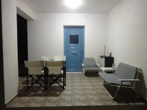 a room with three chairs and a blue door at Theros house in Kythira