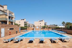 a large swimming pool with lounge chairs and a building at Apartamento Relax and Dream in Pájara