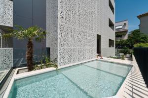 斯普利特Luxury Apartments Villa Mala Split的棕榈树建筑前的游泳池