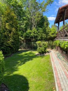 un patio con césped verde y un camino de ladrillo en Domek letniskowy Wielonek 4, en Cierplewo