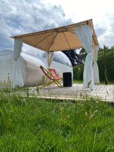 a tent and a chair under an umbrella at Bubble Tent Hotel in Weyregg