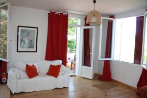 a living room with a white couch and red curtains at À l'ombre du mûrier in Blauvac