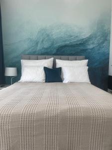 1 dormitorio con 1 cama y una pintura del océano en Rezydencja Niechorze Lazurowy 326 en Niechorze