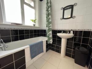 a bathroom with a tub and a sink and a mirror at Bournemouth 3 Bedroom - Parking in Bournemouth