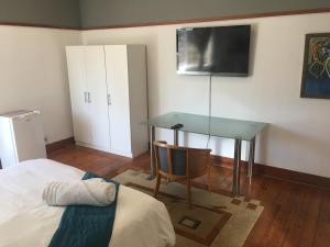 a bedroom with a bed and a desk with a television at 51 on York Guesthouse in Johannesburg