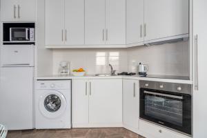 a kitchen with white cabinets and a washer and dryer at Mare Gaia Apartments in Skiathos Town