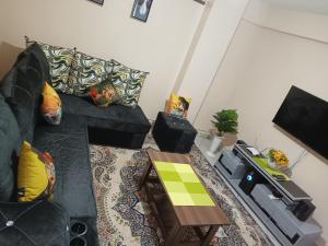 ein Wohnzimmer mit einem schwarzen Sofa und einem Tisch in der Unterkunft J.J homes 1- bedroom apartment, Nairobi in Nairobi