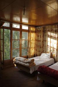 a bedroom with two beds in a room with windows at Thangkop House in Leh