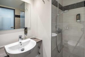 a white bathroom with a sink and a shower at Abasto Hotel Dachau in Dachau