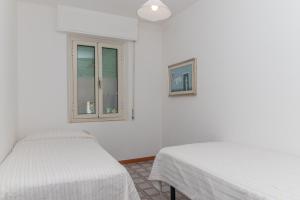 2 bedden in een witte kamer met een raam bij Appartamento Ginepro in Cala Liberotto