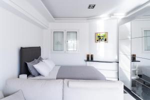 a white bedroom with a bed and a couch at Luxury penthouse , breathtaking Acropolis view in Athens