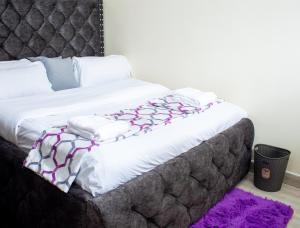 1 dormitorio con 1 cama grande con sábanas moradas y blancas en 1 BR FULLY FURNISHED NAKA en Nakuru