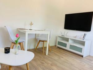 ein Wohnzimmer mit einem weißen Tisch und einem TV in der Unterkunft FEDDERSEN LIVING Kernsanierte Ferienwohnungen - Gemütlich - Netflix - Voll ausgestattet - zentral in Brunsbüttel