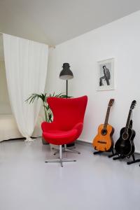 une chaise rouge dans une pièce avec deux guitares dans l'établissement Studio Solbakke, modern studio close to sea, à Rød