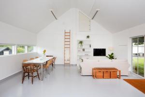 a white living room with a white couch and a table at Studio Solbakke, modern studio close to sea in Rød