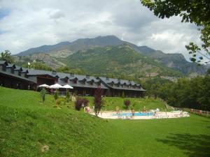 a resort with a swimming pool and mountains in the background at Aparthotel Bubal in El Pueyo de Jaca