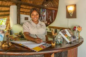 een vrouw die aan een tafel zit en op een papier schrijft bij Pioneer Camp in Lusaka