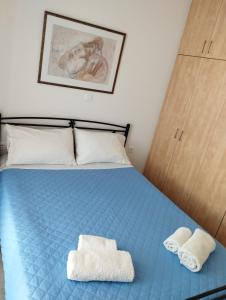 1 dormitorio con 1 cama azul y 2 toallas en Syros House with View, en Ermoupoli