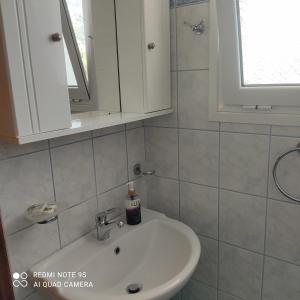 łazienka z białą umywalką i oknem w obiekcie M&L Studios w mieście Valeriános