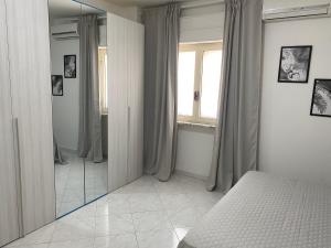 una camera da letto con specchio, letto e finestra di Napoli Residence Casalnuovo a Casalnuovo di Napoli