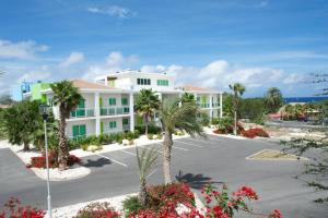 a large white building with palm trees in a parking lot at Piscadera Harbour Village in Willemstad