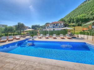 a swimming pool with chairs and a house in the background at Apartments Blazevic in Herceg-Novi