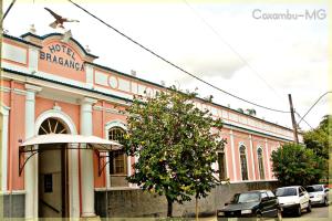 a large pink building with a tree in front of it at Hotel Bragança in Caxambu