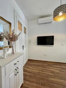 kuchnia z białymi szafkami i telewizorem na ścianie w obiekcie Lux Apartmans w Puli