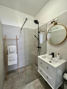 a bathroom with a sink and a shower with a mirror at Lux Apartmans in Pula