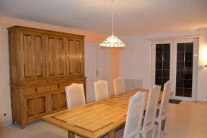 a dining room with a wooden table and white chairs at Gite HANSEL de la Ferme du Schneeberg in Wangenbourg