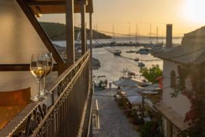 a glass of wine sitting on a balcony overlooking a harbor at Virvilis Apartments in Syvota