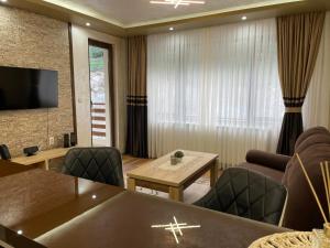 uma sala de estar com uma mesa e cadeiras e uma televisão em Апартамент ВАНЕСА em Velingrad