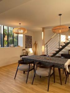 a dining room with a table and chairs and a staircase at Domaine des Pousses, gîte au coeur d'un village de campagne in Droue-sur-Drouette