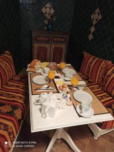 a table with plates and cups and oranges on it at Riad La Rose Des Vents in Essaouira