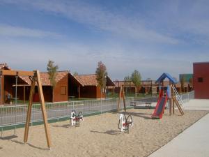 un parque infantil con columpios y toboganes en la arena en Camping Iratxe Ciudad de Vacaciones, en Ayegui