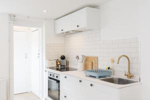 a kitchen with white cabinets and a sink and a window at Central quiet cottage. Walk to shops, bars & beach in Brighton & Hove