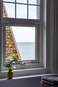 a window with a view of the ocean through it at Beach View Luxury Apartment in Lyme Regis