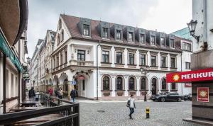 un hombre caminando en una calle frente a un edificio en Hotel Radnice, en Liberec