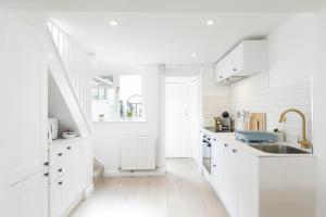 a white kitchen with white cabinets and a sink at Central quiet cottage. Walk to shops, bars & beach in Brighton & Hove