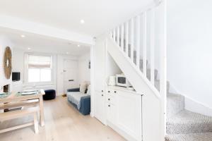 a white room with a bed and a staircase at Central quiet cottage. Walk to shops, bars & beach in Brighton & Hove
