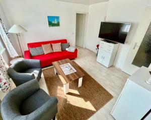 Sala de estar con sofá rojo y mesa de centro en Haus Ostseeblick, en Lohme