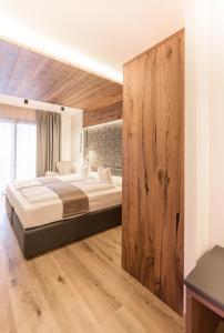 a bedroom with a large bed and a wooden wall at Cevedale Living Romance Hotel in Cogolo