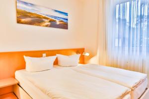 um quarto com uma cama com lençóis brancos e uma janela em Apartment Ostseerose ein Strandkorb ist im Sommer inclusive em Zempin