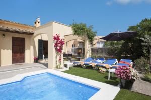 een achtertuin met een zwembad en stoelen en een parasol bij Villa Oleanda by Villa Plus in Port d'Alcudia