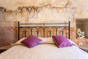 a bed with two purple pillows on top of it at Dimora la Pinta ‘700 in Gallipoli